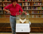 Emily Stopp neben der Vitrinenpräsentation "Eine Bibliothek für Frauen in Weimar" im Bücherkubus des Studienzentrums der Herzogin Anna Amalia Bibliothek
